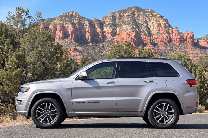 Silver SUV parked on road with red rock formations in the background.